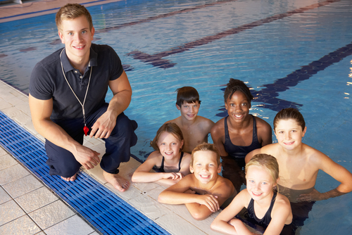 swim team in water with coach nearby