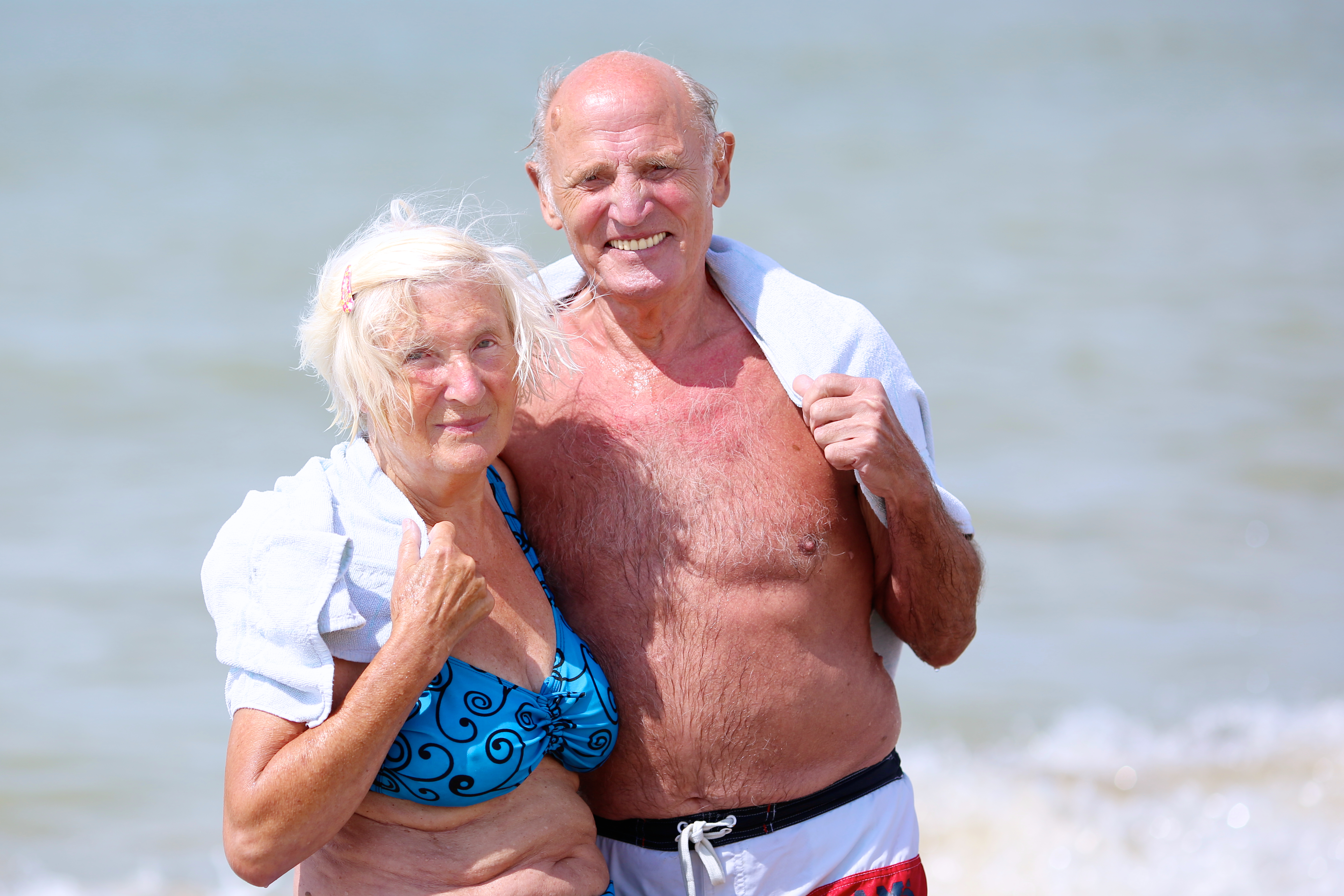 elderly couple on the beach after the polar bear plunge wrapped in a custom woven towel