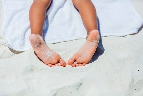 child feet on white towel on beach