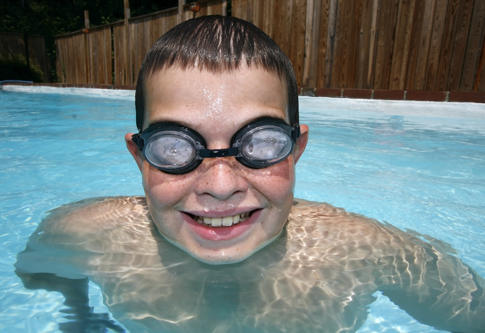 close-up of a happy young boy in swimming pool with goggles