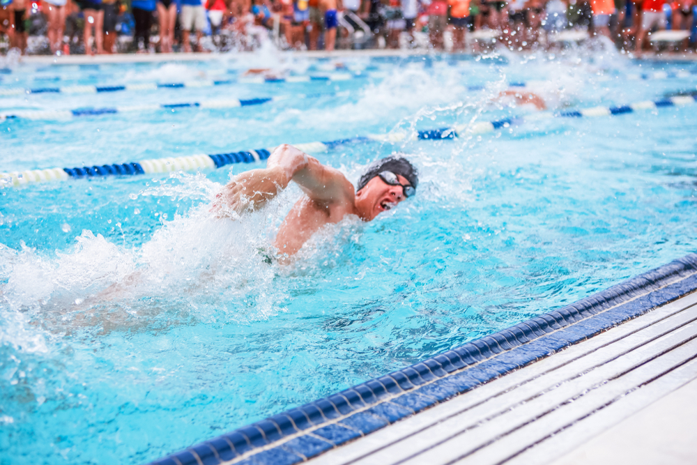 Motion blurred freestyle swimmer in a race, shallow focus on swimmers hand